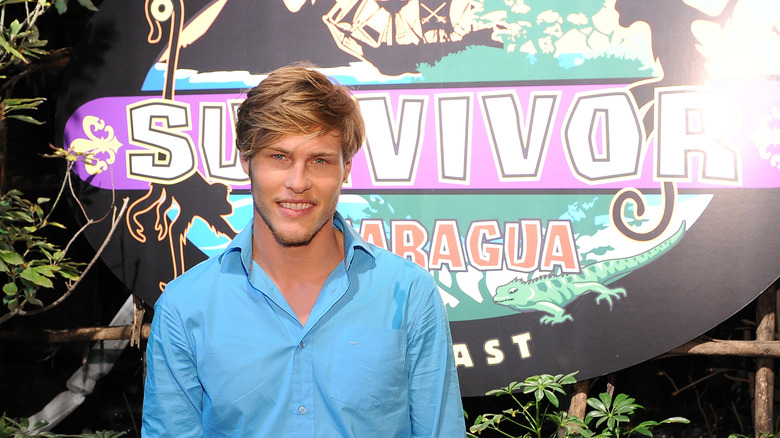 Judson 'Fabio' Birza posing in front of the Survivor logo