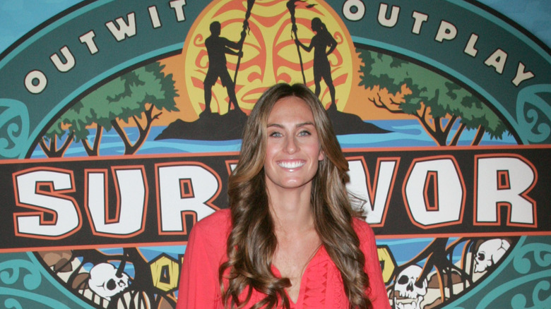 Kim Spradlin posing in front of the Survivor logo
