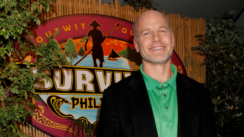 Michael Skupin posing in front of the Survivor logo