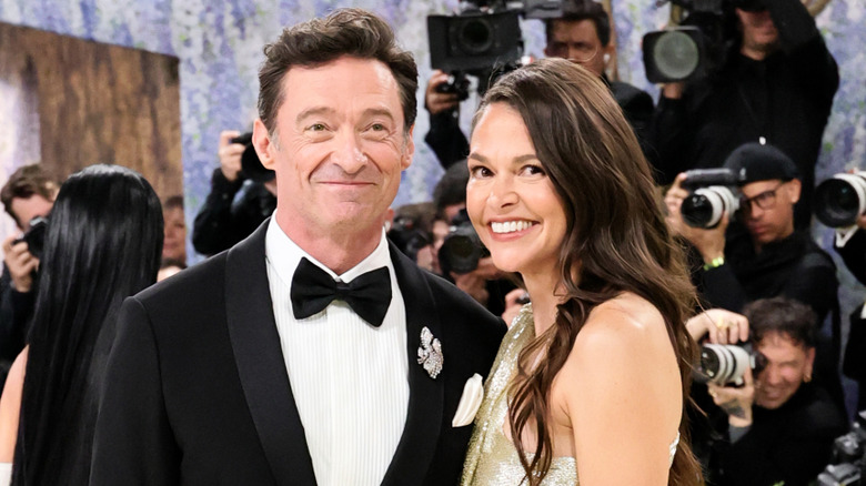 Hugh Jackman and Sutton Foster smiling with cameras behind them at the 2026 Met Gala.