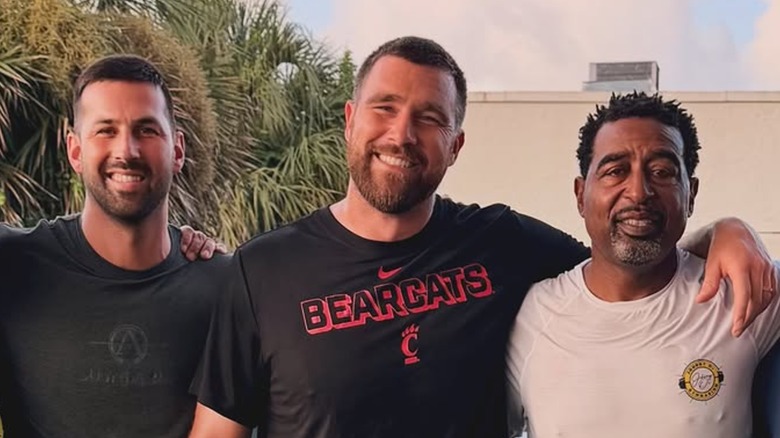 Travis Kelce smiling while posing with a couple of his pals