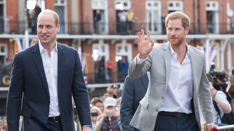 Prince Harry (R) waves to the crowd while walking with Prince William (L)