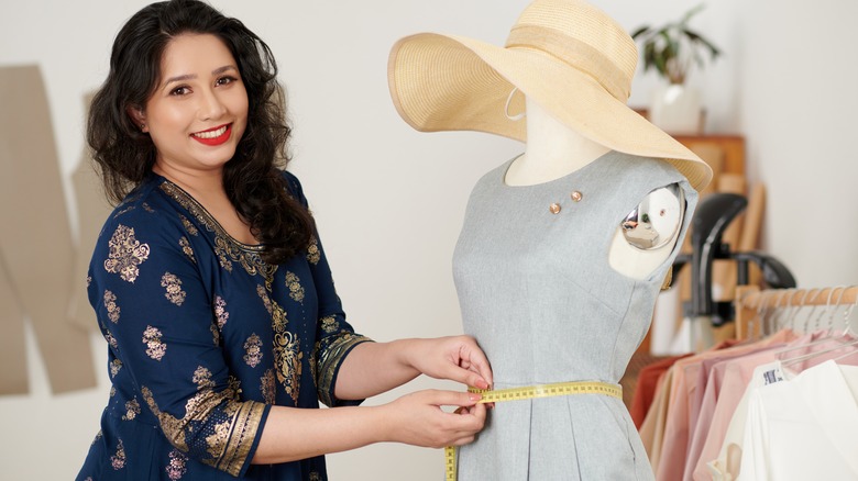Woman measuring dress on tailor's dummy