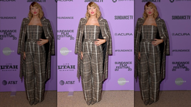 Taylor Swift wearing a plaid jumpsuit and matching coat.