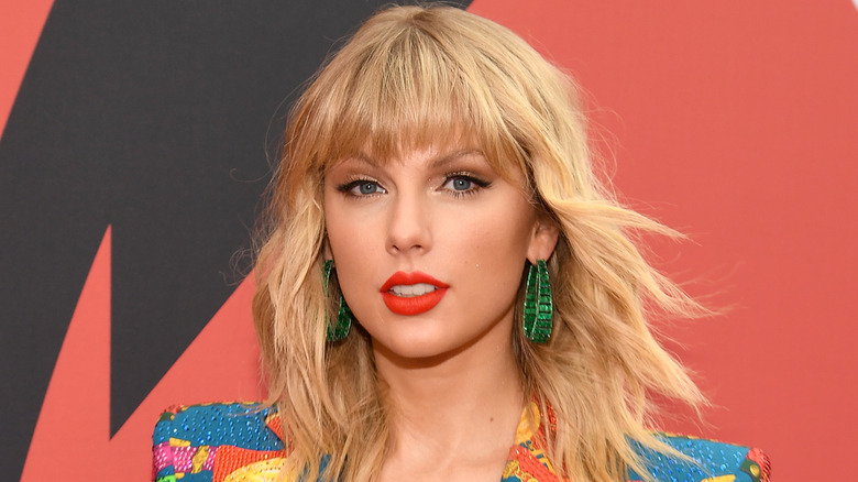 Taylor Swift wearing green hoop earrings.