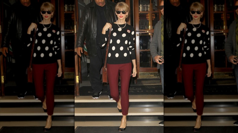 Taylor Swift wearing a black and white polka dot sweater and red pants.