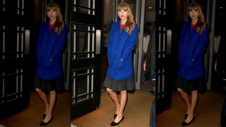 Taylor Swift wearing a blue coat and gray skirt.