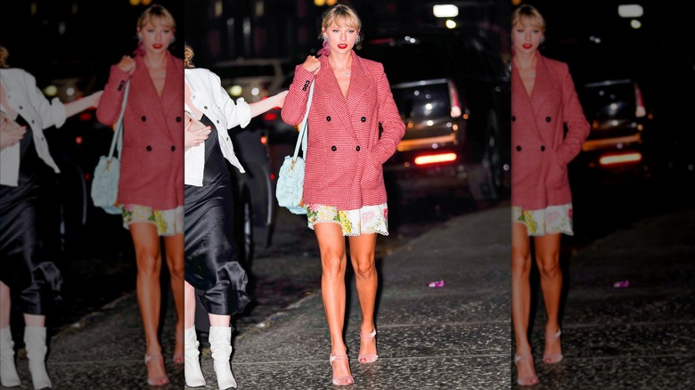 Taylor Swift wearing a red houndstooth coat over a floral dress.
