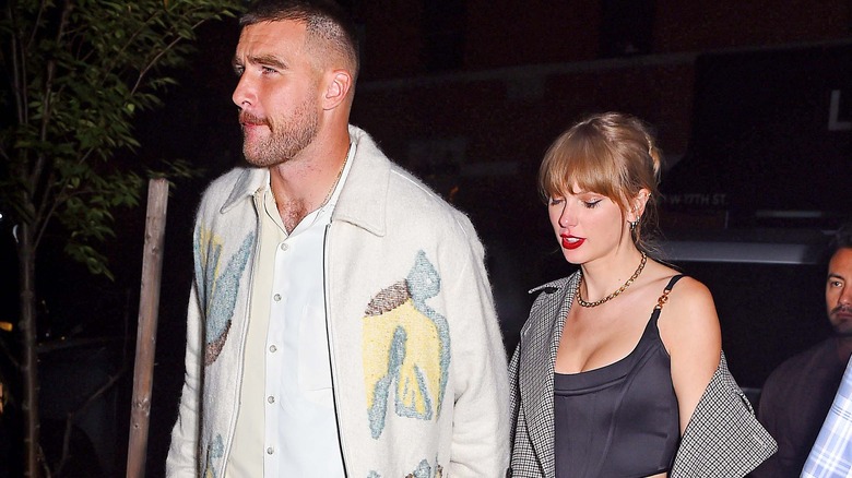 Travis Kelce leading Taylor Swift out of a car 