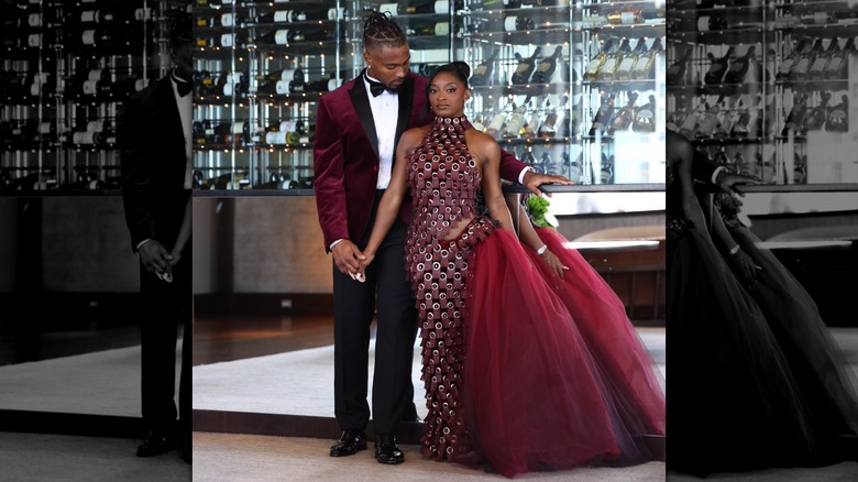Simone Biles hand-in-hand with Jonathan Owens, both wearing burgundy