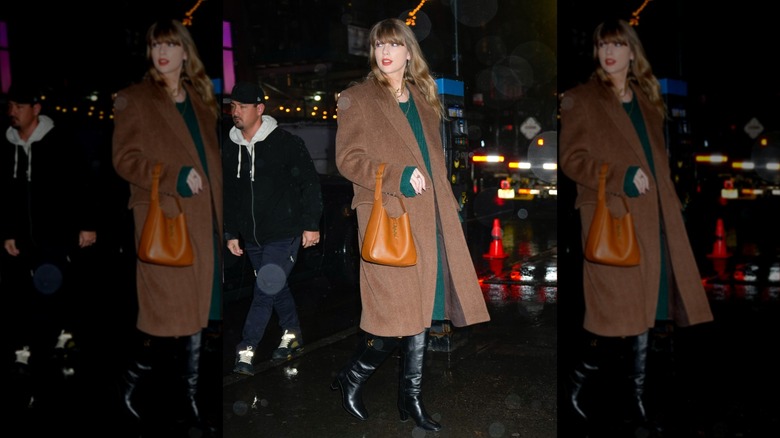 Taylor Swift in a brown coat and an orange bag with black boots