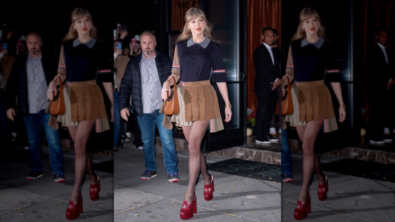 Taylor Swift in a brown mini skirt and a blue top and red platform heels outside