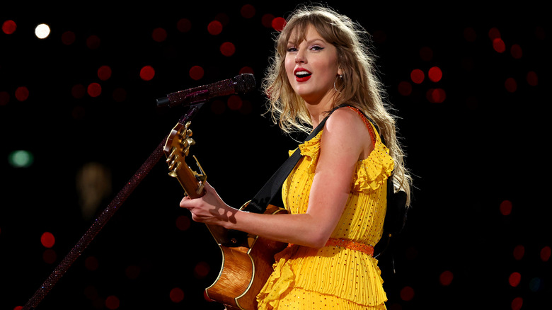 Taylor Swift playing guitar in yellow dress