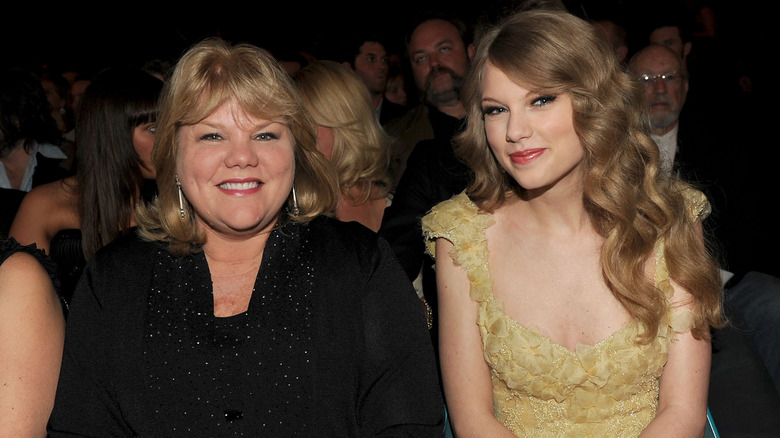 Andrea and Taylor Swift smiling together while sitting in a crowd