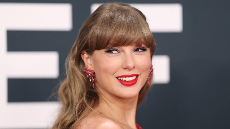 Taylor Swift smiling and looking back in a pose.