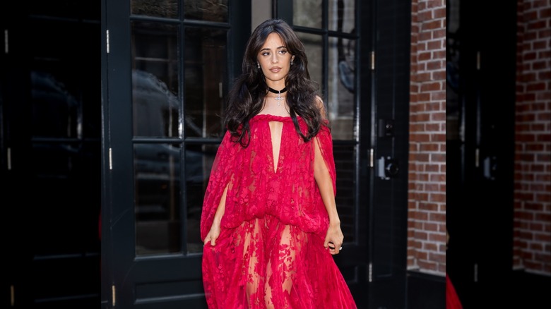 Camila Cabello wearing a red sheer dress and a choker with a silver cross on it.