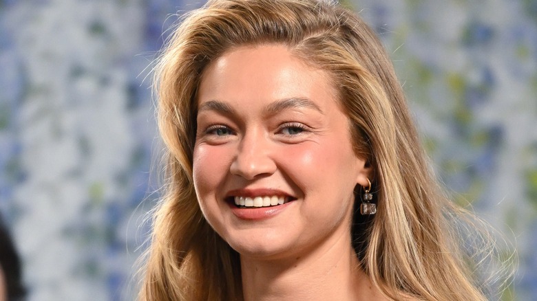Gigi Hadid smiling with a diamond earring on her left ear.