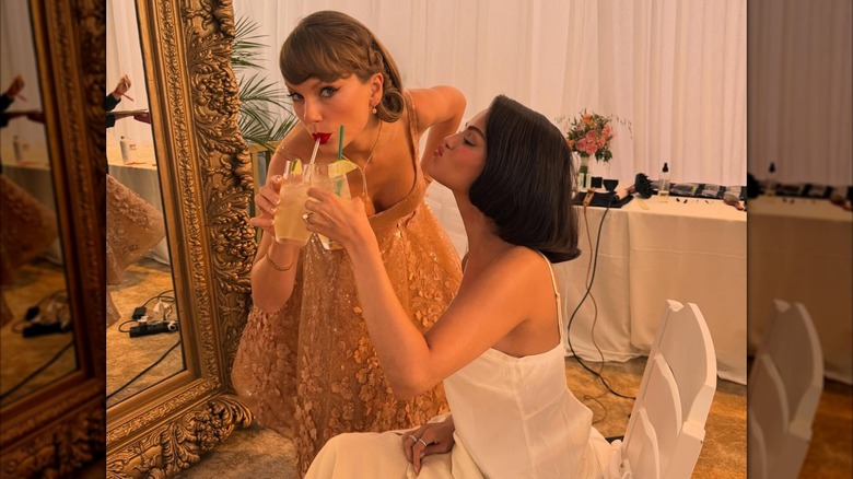 Taylor Swift sipping a drink next to Selena Gomez.