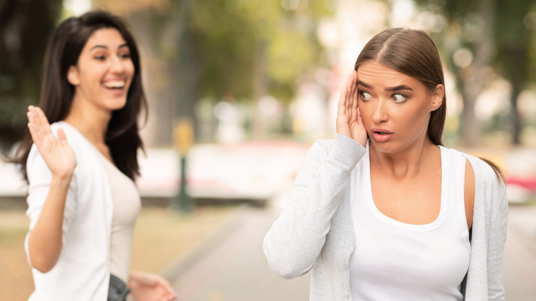 Woman ignoring her friend waving