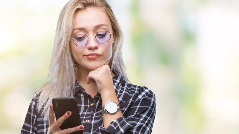 woman texting while looking unsure