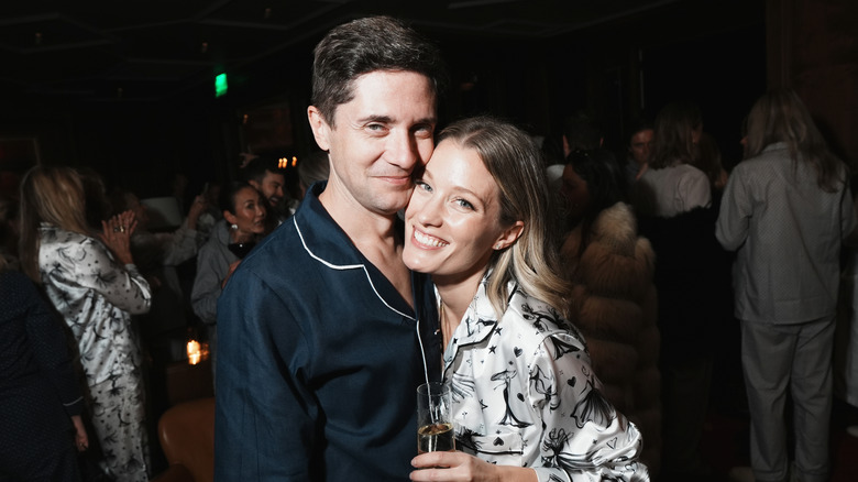 Ashley and Topher Grace pose cheek to cheek at a pajama party holding a flute of champagne