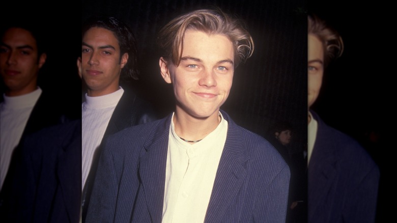 Leo DiCaprio smiles in a white t-shirt and blue jacket