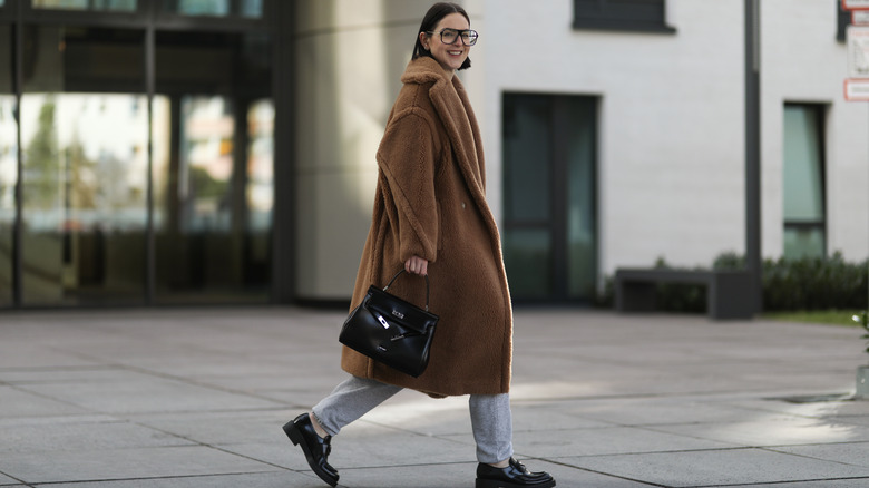 Woman walking with oversized coat and gray sweatpants