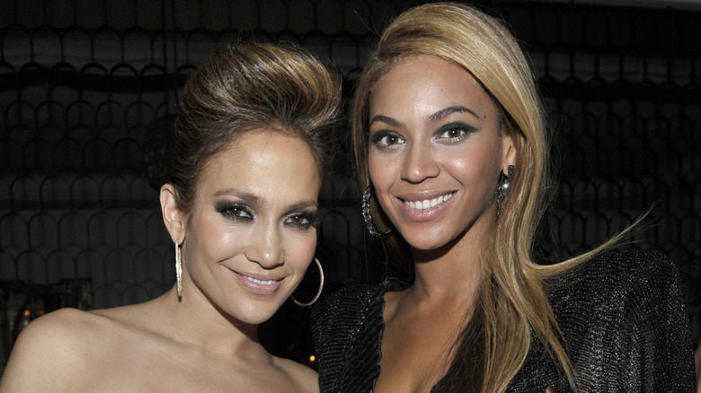 Jennifer Lopez and Beyoncé smiling and wearing hoop earrings