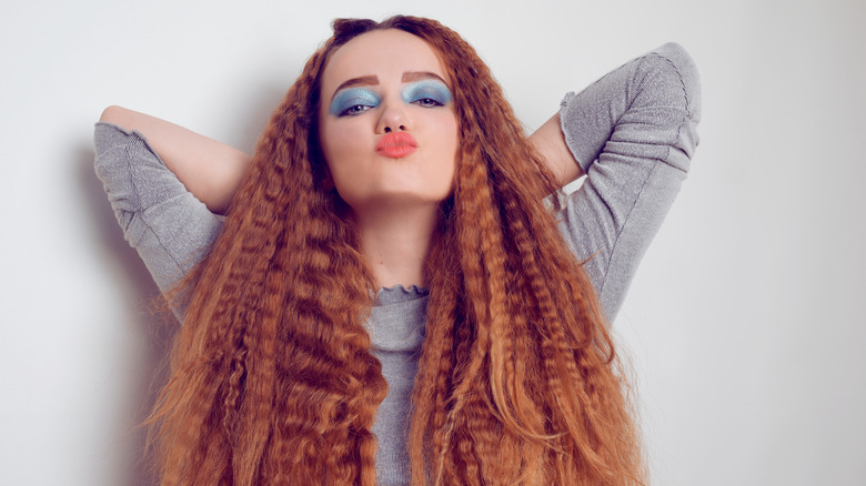 Girl with red hair and blue eyeshadow wearing voluminous, crimped hairstyle