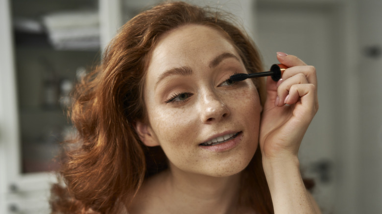 red head putting on mascara