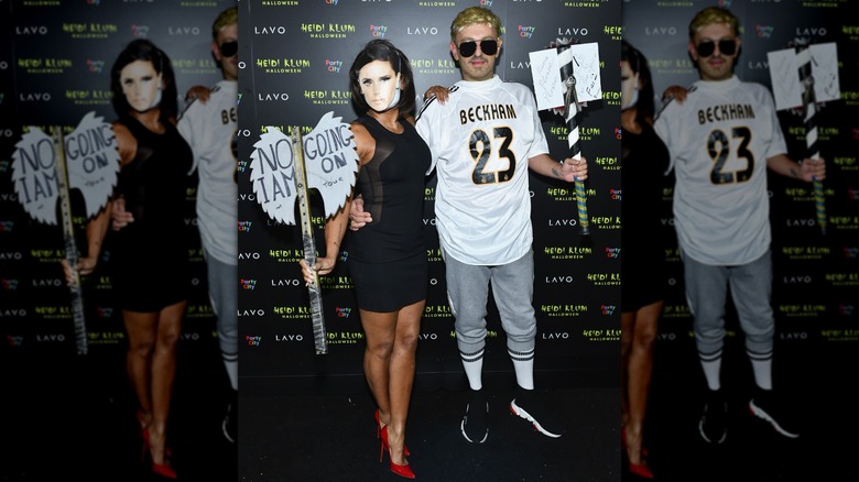 Mel B wearing a Victoria Beckham mask and posing with Gary Madatyan, who is wearing a David Beckham costume