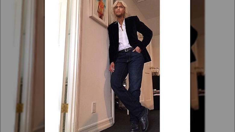 Tyra Banks dressed as Richard Branson in a blond wig and black blazer and sporting fake facial hair