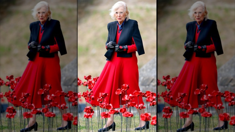 Queen Camilla in red and black walking among poppies