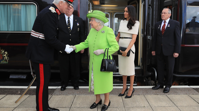 Queen Elizabeth II and Meghan Markle exiting a train in 2018