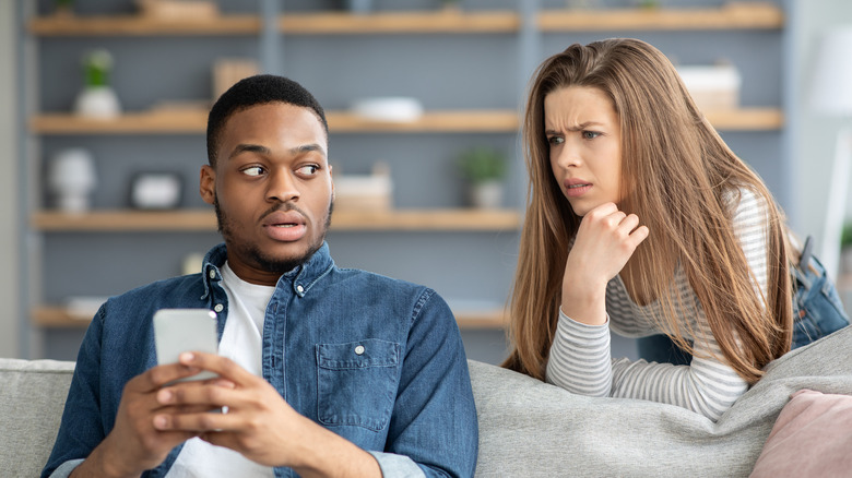 Woman angry at boyfriend holding phone