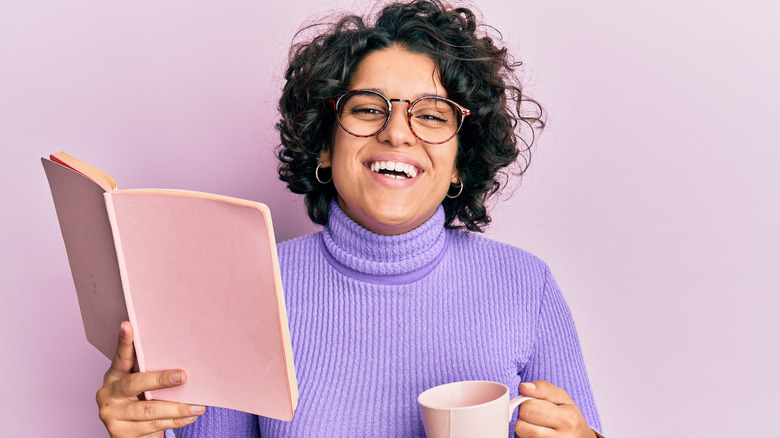 Hispanic woman smiling with open pink book in hand