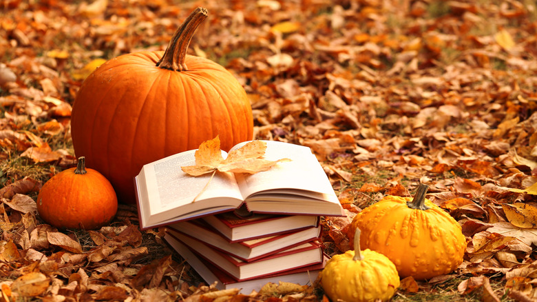 stack of books in fall leaves 