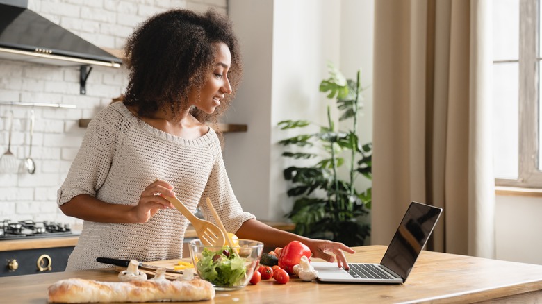 Woman looking at computer while cooking