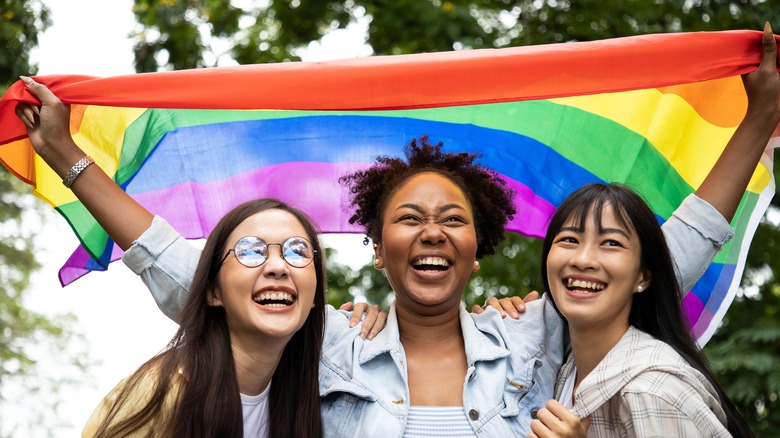 Friends waving LGBTQ+ rainbow flag 