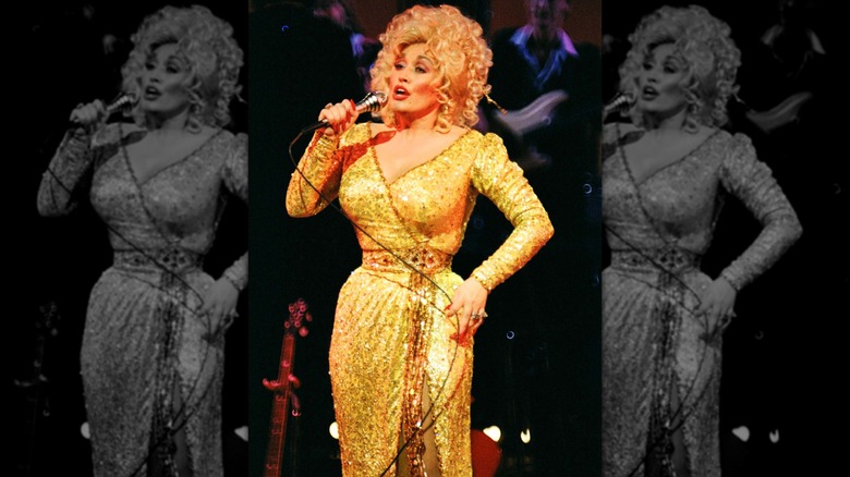 Dolly Parton singing into a microphone while wearing a gold dress