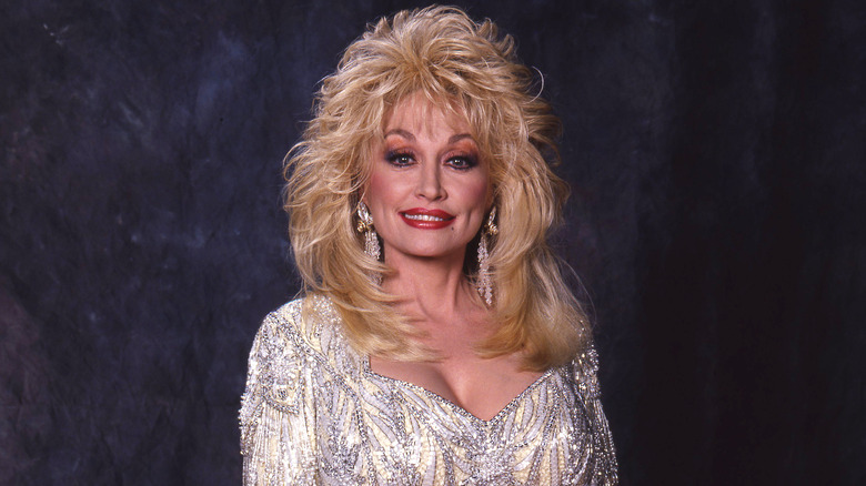 Dolly Parton smiling while posing in a glittery silver dress