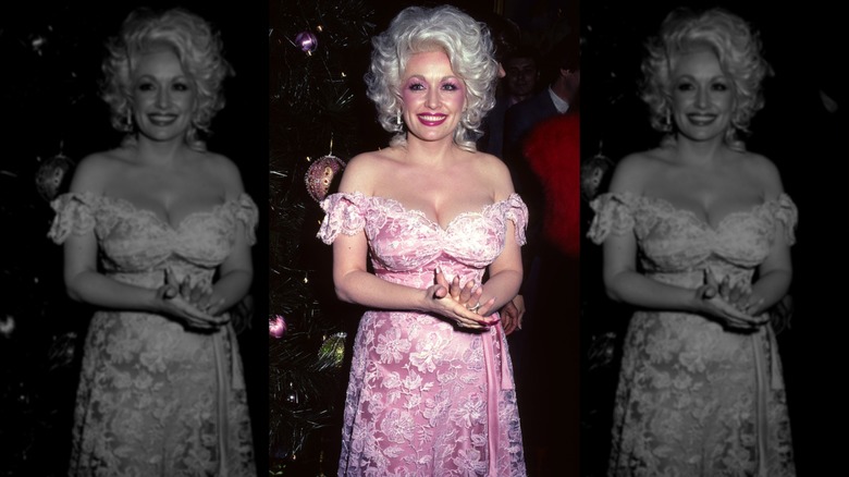 Dolly Parton smiling while wearing an off the shoulder pink floral dress