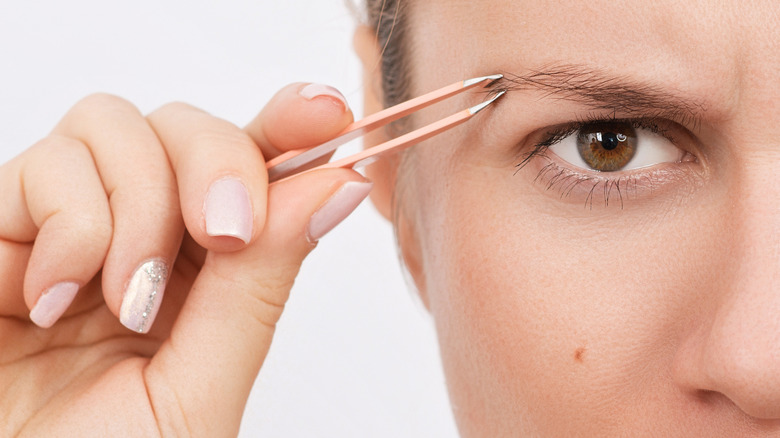 Unhappy woman plucking her eyebrows