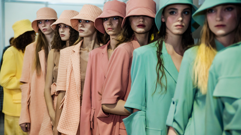 Models lined up wearing hats