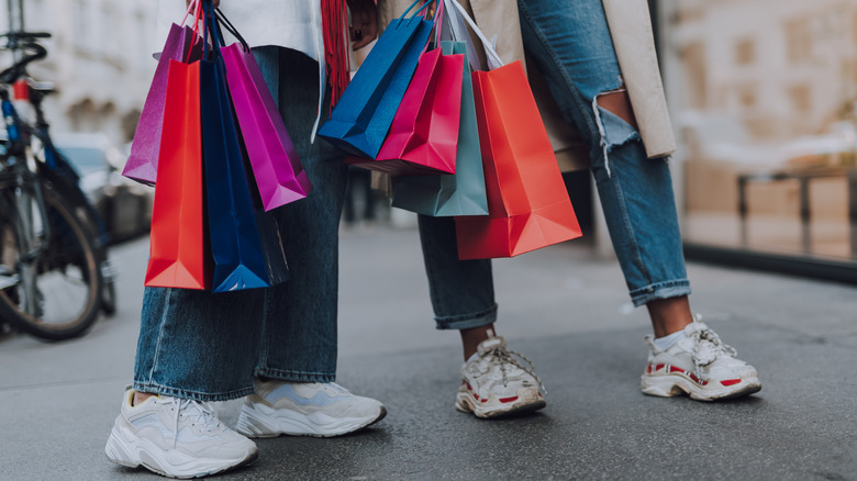 women wearing sneakers, holding shopping bags