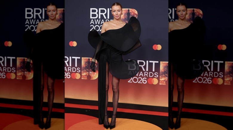 Olivia Attwood posing in a black minidress with sculptural elements shaped like curved potato chips.