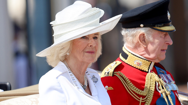 Queen Camilla sitting with King Charles in carriage at Trooping the Colour, wearing a scrunchy white hat