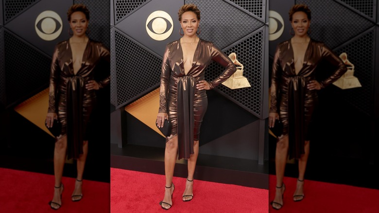MC Lyte posing in a bronze dress with a plunging neckline, long sleeves, and draped detail on the front
