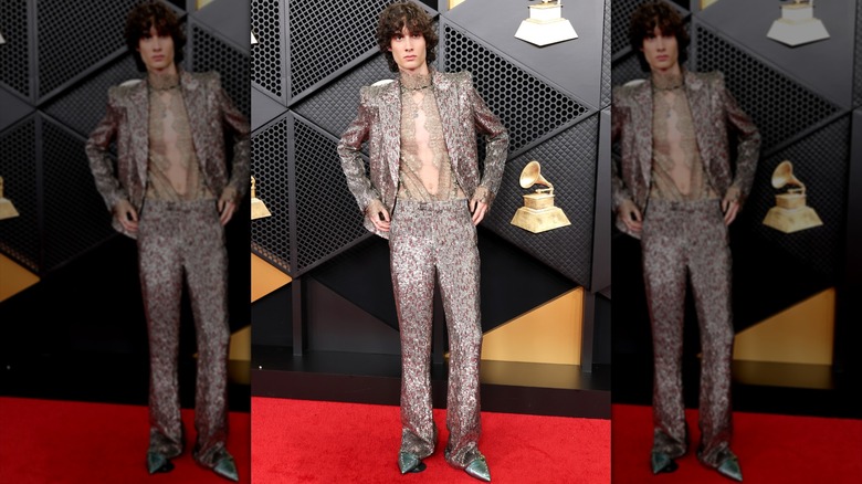Sombr posing in a silver embroidered suit and sheer lace shirt at the 2026 Grammy Awards.