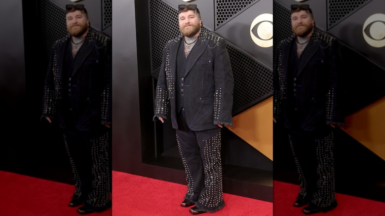 Teddy Swims posing in a dark denim suit covered with silver studs